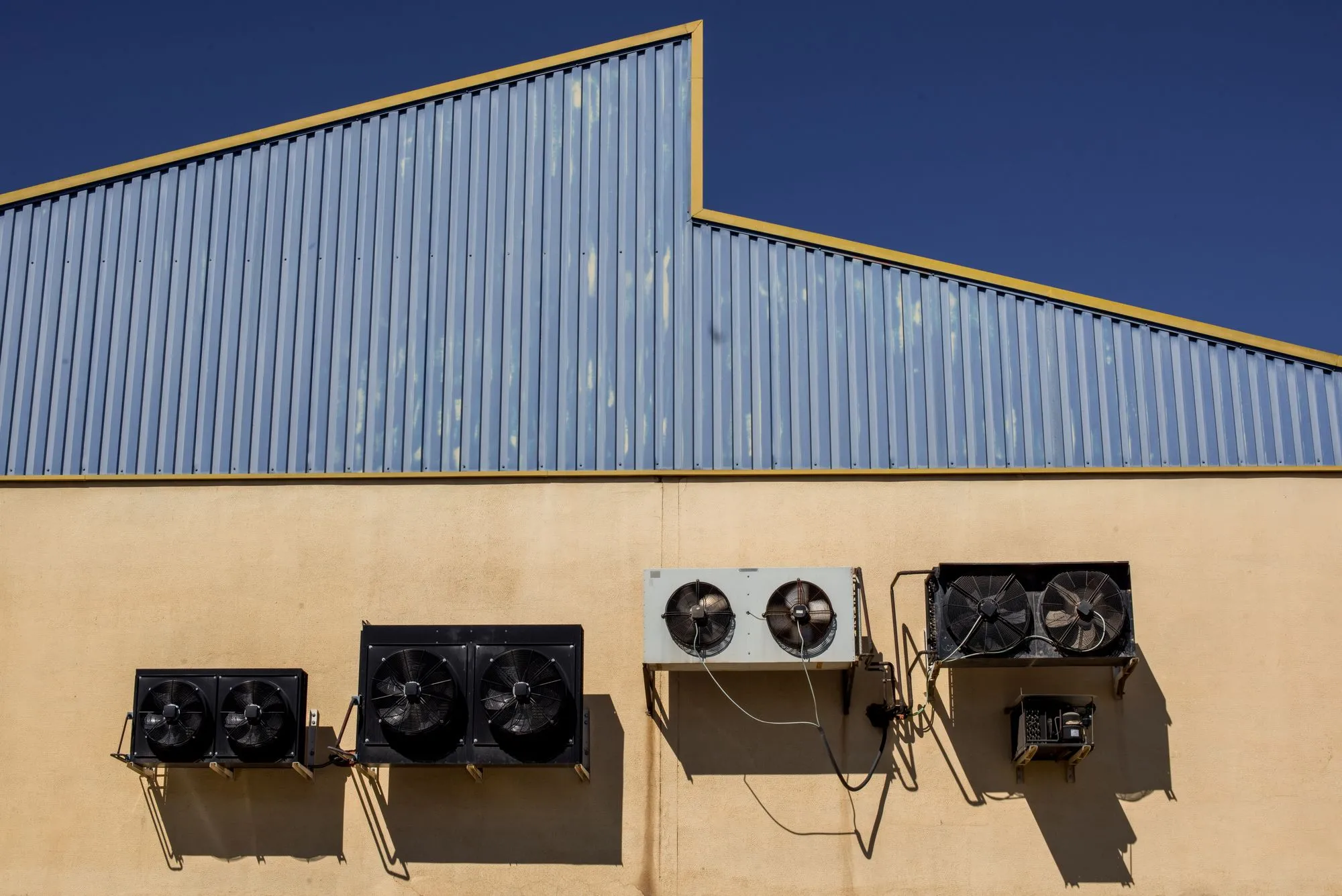 Three commercial rooftop HVAC units mounted on a flat warehouse roof in Dallas
