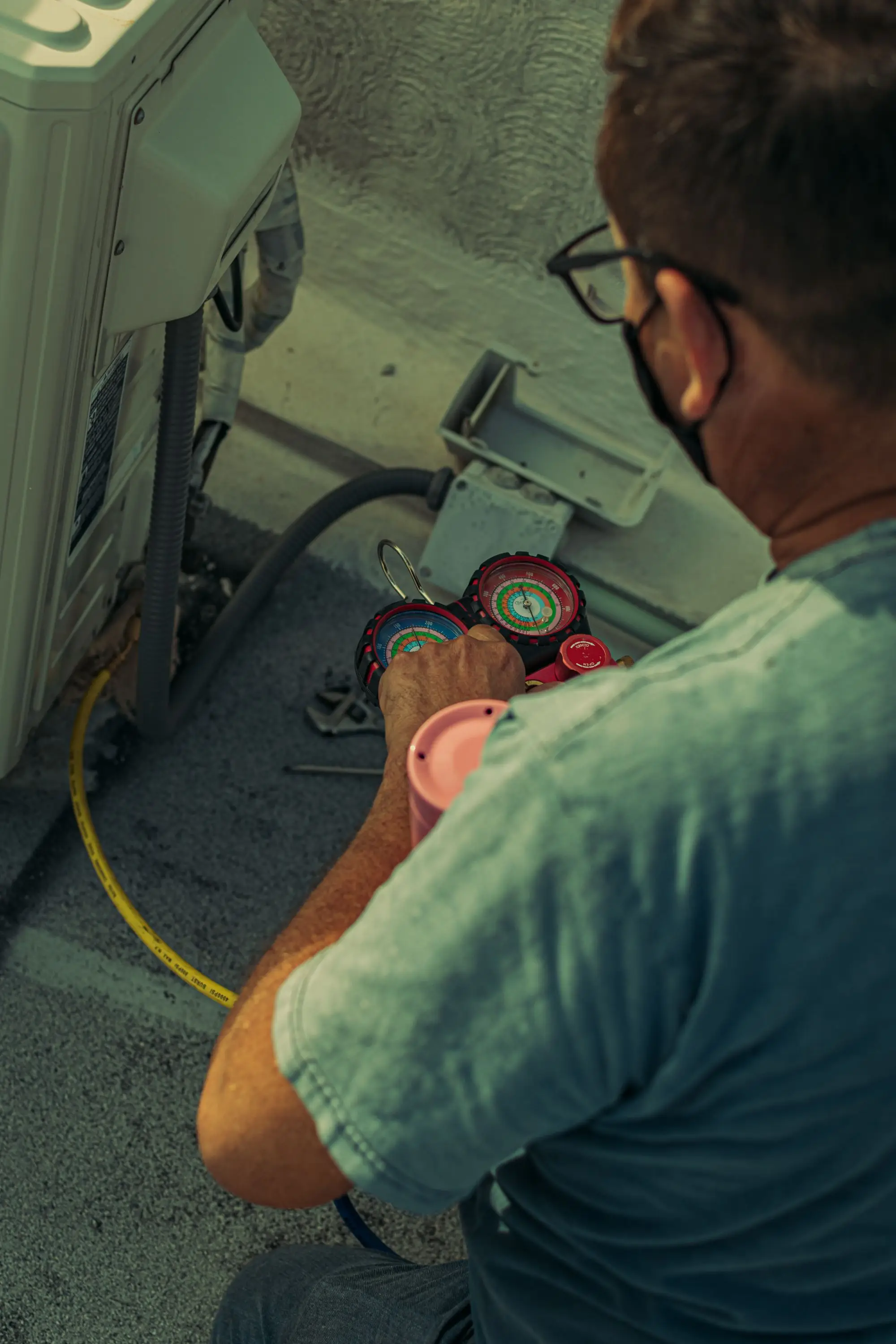 HVAC technician checking refrigerant gauges during a preventive maintenance visit on a commercial rooftop unit